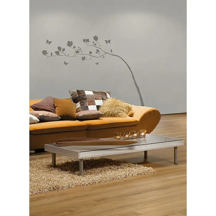 Komar Dekosticker Arabesque - 7 -tlg., 100 x 70 cm - Wohnzimmer mit orangefarbenem Sofa, Kissen und Couchtisch mit Glasplatte auf einem beigen Teppich. Elegantes Design für ein gemütliches Zuhause.