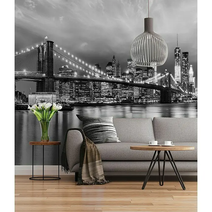 Komar Home Fototapete Brooklyn B/W - 8 -tlg., B x H: 368 x 254 cm, Papier - Eine stilvolle Inneneinrichtung mit einem modernen Sofa, einem eleganten Beistelltisch und einem dekorativen Lampenschirm vor einer Skyline-Tapete.