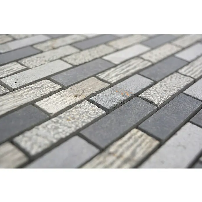 Mosaikfliese Brick Carving Mix XNC B49 - 30,5 x 30,5 cm, Grau, Matt - Nahaufnahme von grauen und weißen Pflastersteinen, die ein geometrisches Muster bilden und eine moderne, robuste Oberfläche zeigen.